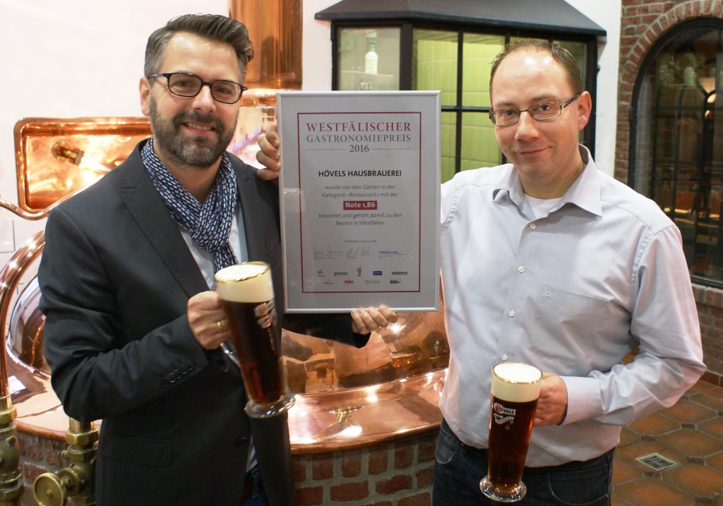 Marcus Besler (li.) überreichte Hövels-Betriebsleiter Manuel Chlinch (re.) die Urkunde vom diesjährigen Westfälischen Gastronomiepreis mit der Note „sehr gut“.